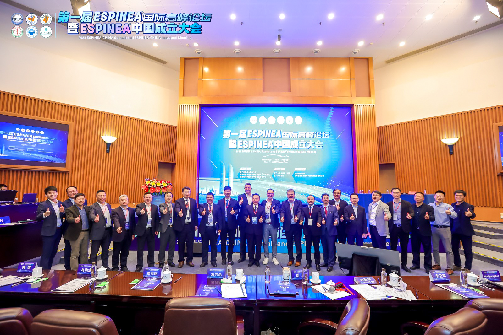 Group Picture of many asian doctors in dark suits standing in the middle of a big hearing room